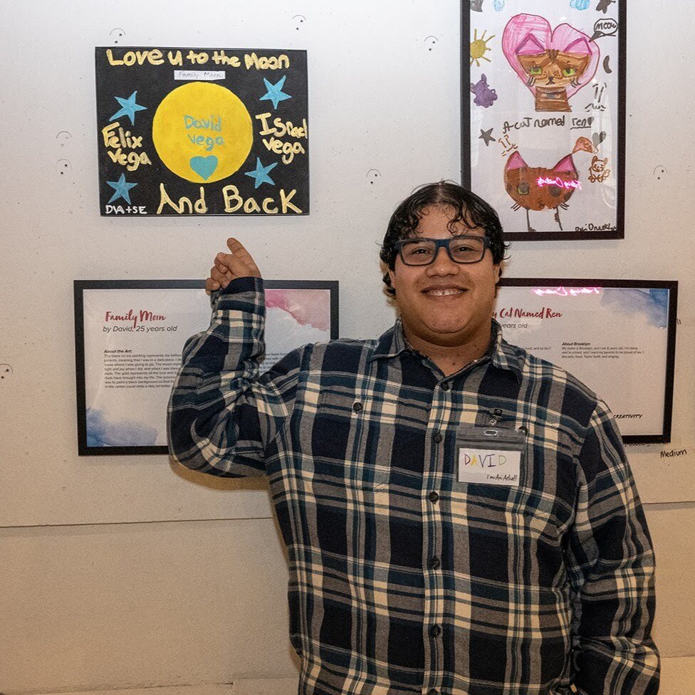 David points to his artwork on display at Fostering Creativity
